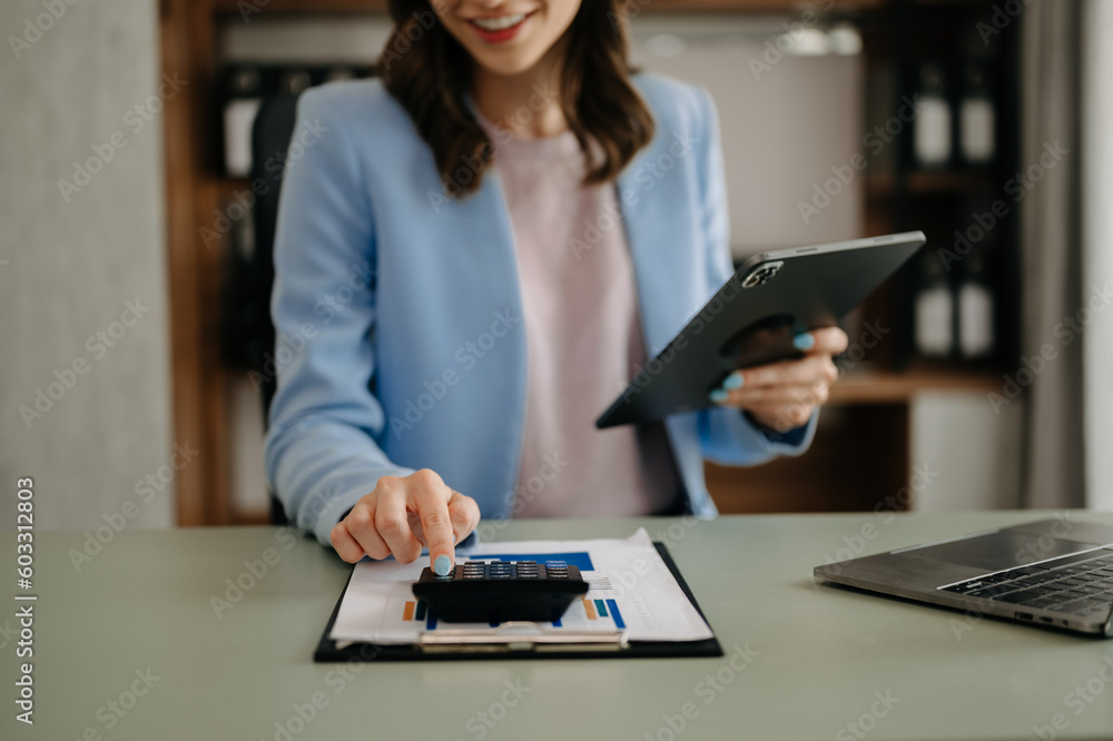 Business woman sitting front tablet ,laptop computer with financial graphs and statistics on monitor.at modern office Business woman sitting front tablet ,laptop computer with financial graphs and statistics on monitor.at modern office