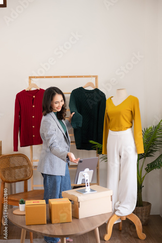Fashion blogger concept, Young Asian women selling clothes on video streaming.Startup small business SME, using smartphone or tablet taking receive and checking..