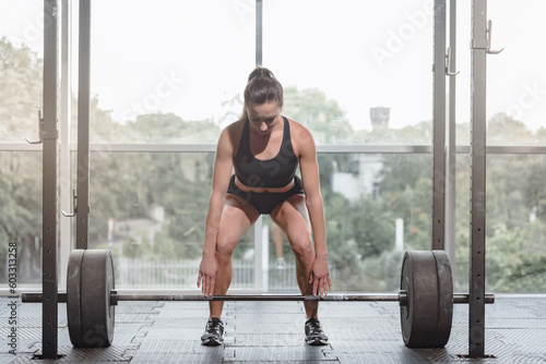 Portrait of young strong attractuve woman doing heavy weight lifting workout photo