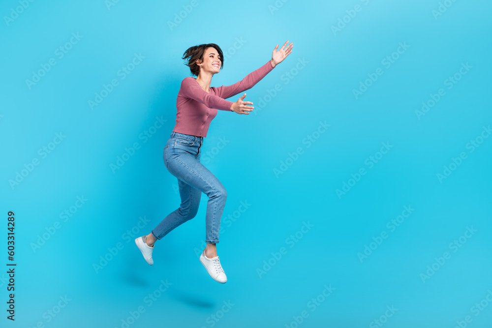 Full body profile portrait of cheerful nice lady jump run raise hands catch empty space isolated on blue color background