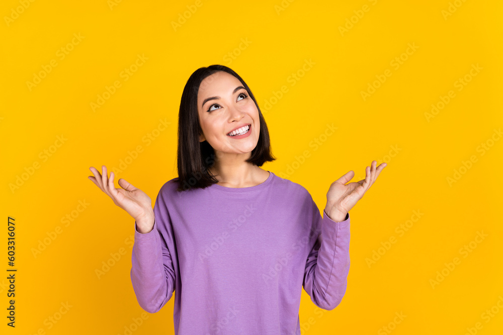Photo of young korean positive cheerful lady trendy shirt hands hold look up interested shopping offer isolated on yellow color background Photo of young korean positive cheerful lady trendy shirt hands hold look up interested shopping offer isolated on yellow color background