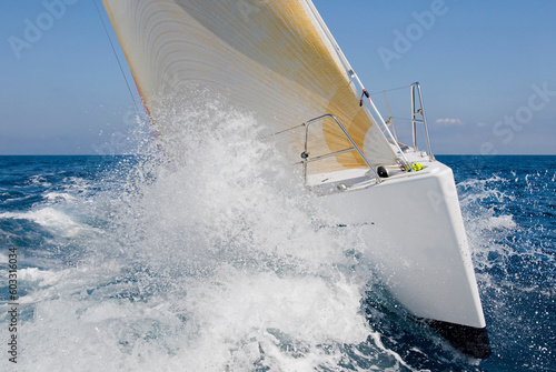 Prua di barca a vela con onde e spruzzi, lo scafo della barca a vela rompe le onde del mare blu photo