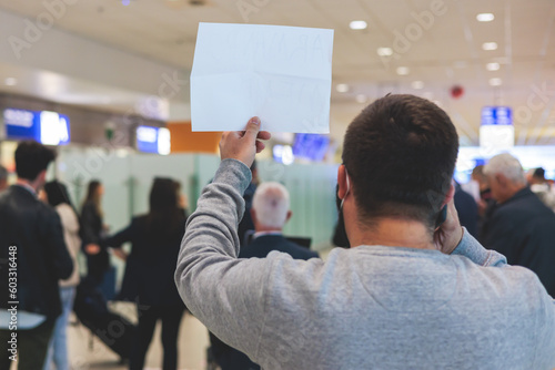 Meeting at the airport, person holding a placard card sign with welcome title text, greeting passenger on arrival, holding a name plate to receive a traveler, arrival area at international terminal