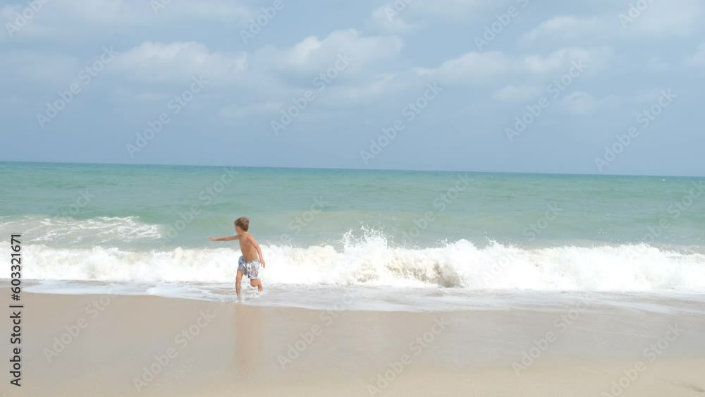 happy boy running away from the sea waves, holidays at sea happy boy running away from the sea waves, holidays at sea