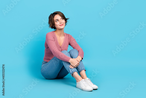 Full length portrait of cute minded person sit floor look empty space contemplate isolated on blue color background