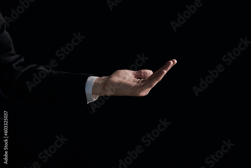 Man's hand shows a gesture with a palm on a black background.