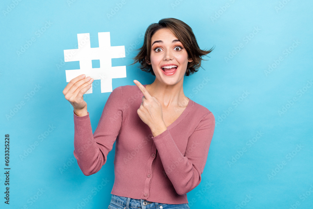 Photo of sweet impressed woman dressed pink shirt pointing finger hash tag isolated blue color background Photo of sweet impressed woman dressed pink shirt pointing finger hash tag isolated blue color background