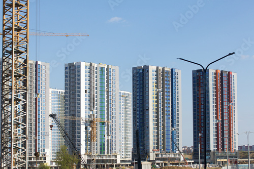 Construction site. Reinforced concrete frames of multi-storey buildings and construction cranes. The final stage of construction. Against the background of the blue sky.
