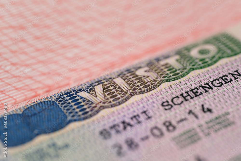 Obraz premium close-up part of page of document, foreign passport for travel with European visa, tourist schengen visa stamp with hologram with shallow depth of field, passport control at border, travel in Europe
