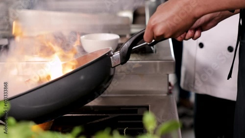 Hands of professional chef show cooking Asian food on frying pan with oil, chef cooking in commercial kitchen or cuisine with uniform, lifestyle chef gourmet working in restaurants with unrecognizable