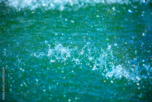 Water background, blue sea water. Beautiful texture of sun glare on the water and sea foam.