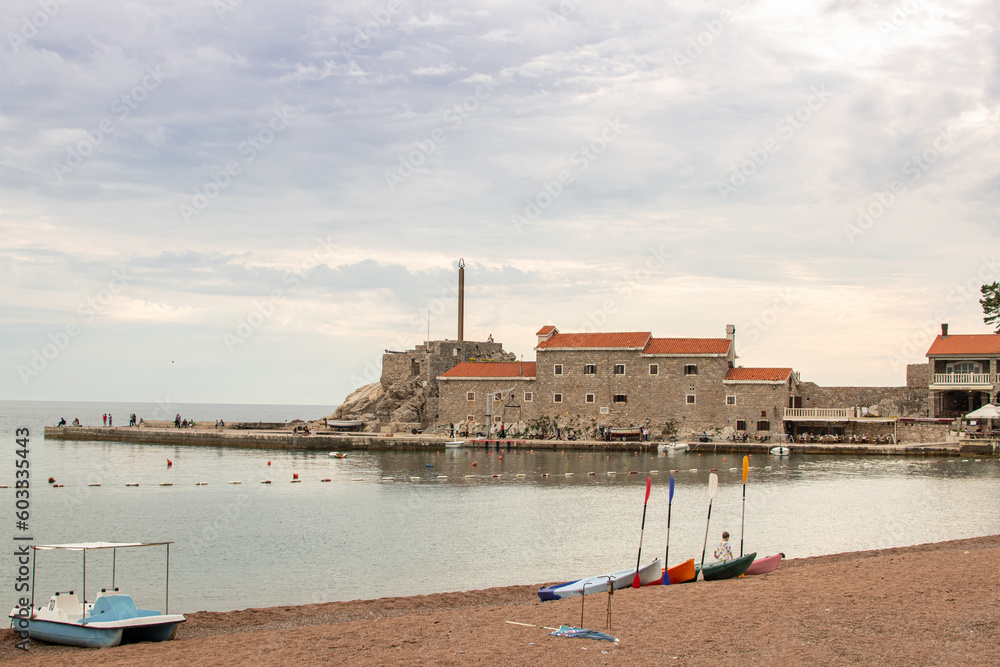 Old town coastal, calm sea water, boats on the sand beach with clouds above. Mediterranean landscape scenery.