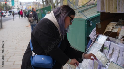 Paris, France - 3 May 2023. Side view of young woman purchases French newspaper from newsstand. Female buying at press kiosk French newspaper. Political, social economic and sport newspapers photo