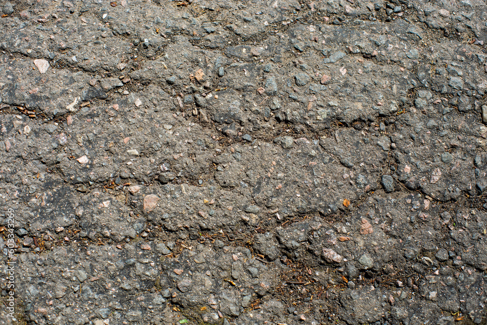 A network of black cracks on the asphalt surface. Road texture with weathered surface, showcasing the effects of time and wear A network of black cracks on the asphalt surface. Road texture with weathered surface, showcasing the effects of time and wear
