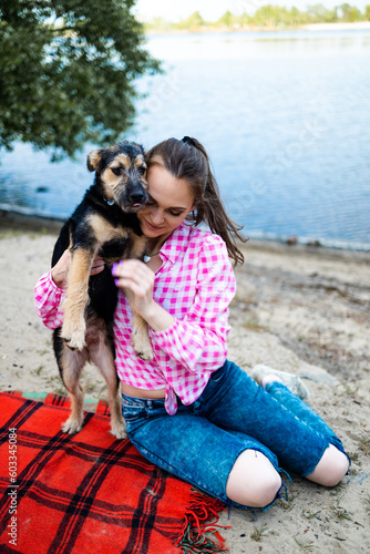 Beautiful young woman playing with her young dog in the park outdoors. Life style portrait.