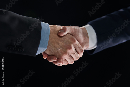 Men shaking hands. Confident businessman shaking hands on black background © Katsiaryna