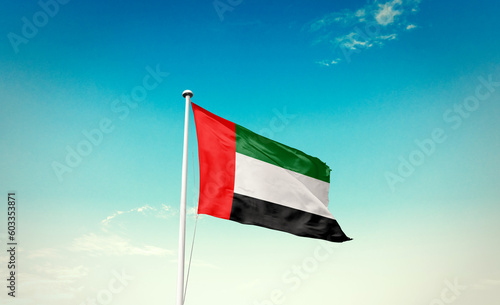 Waving Flag of United Arab Emirates in Blue Sky. The symbol of the state on wavy cotton fabric. photo