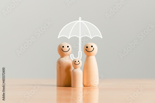 Fotografie Happy family under the umbrella on raining wooden figurine model on table top background
