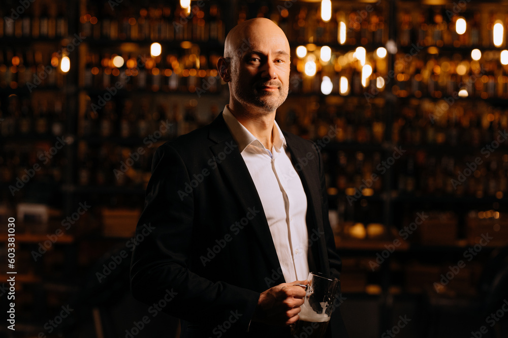 Portrait of a handsome mature gentleman in an evening restaurant. A man in a suit in an evening pub, restaurant, bar