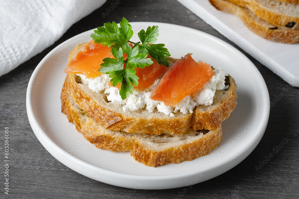 Sandwich with salted salmon and cottage cheese on a gray wooden table