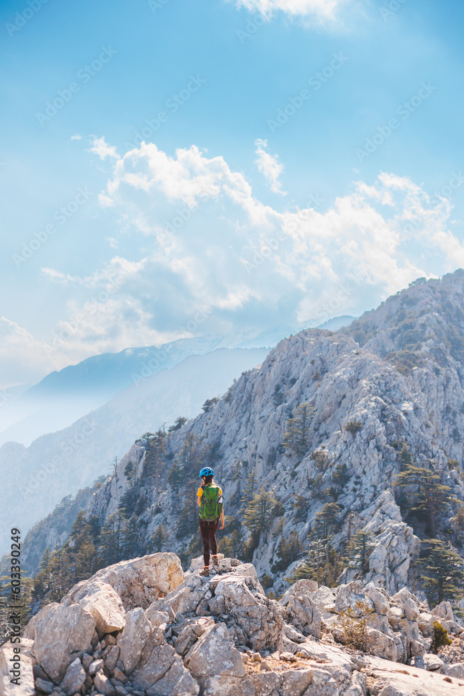 The girl is climbing the rock. Woman climber with a backpack and a helmet in the mountains. adventure and mountaineering concept. hiking with a backpack. mountains of Turkey..
