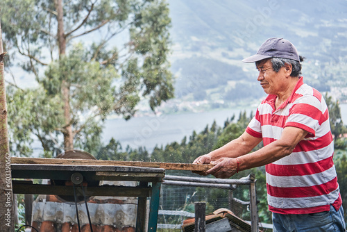 Ethnic male woodworker putting plank on table in farmland photo