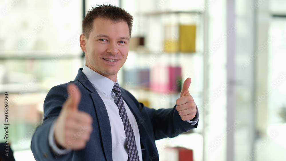 Happy smiling businessman showing thumbs up gesture in office. Successful career growth in business concept Happy smiling businessman showing thumbs up gesture in office. Successful career growth in business concept