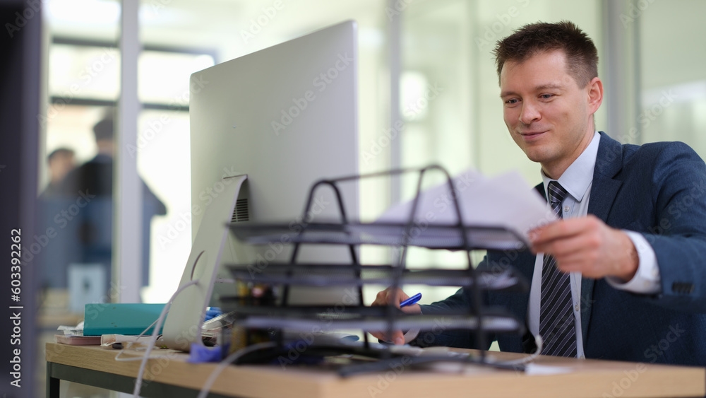 Businessman putting paper documents on stand on table in office. Business paperwork concept Businessman putting paper documents on stand on table in office. Business paperwork concept