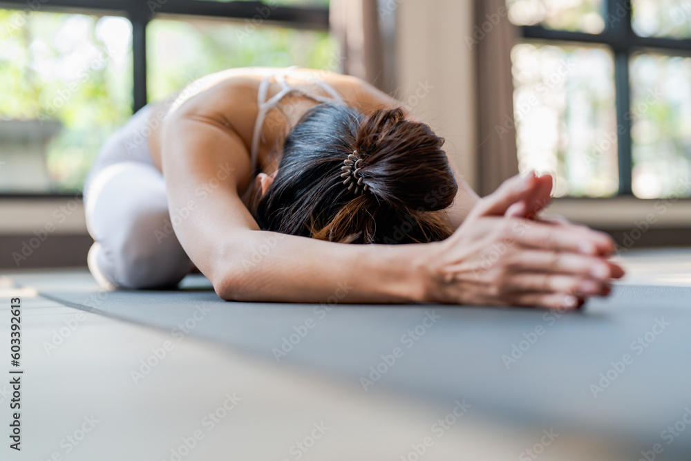 Fototapeta premium Fitness asian woman doing yoga stretching exercise on mat yoga fitness exercises. Healthy lifestyle Calmness and relax at yoga studio.
