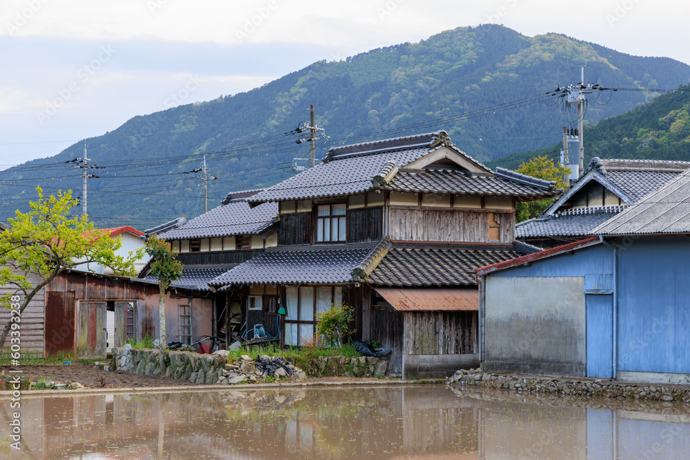Traditional Japanese wooden house by flooded rice field in small town Traditional Japanese wooden house by flooded rice field in small town