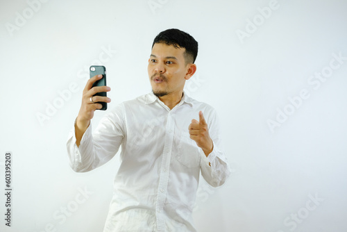 Adult Asian man holding mobile phone showing enthusiastic expression