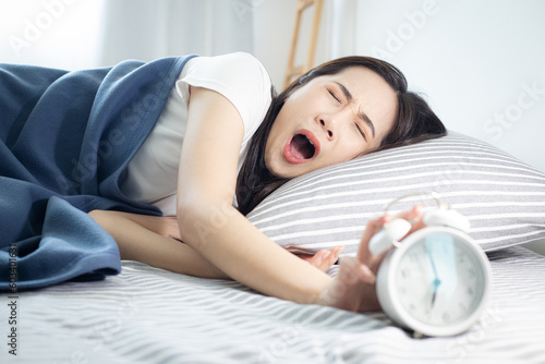 Fotografía Beautiful sleeping Asian woman resting in bed and trying to wake up with alarm clock