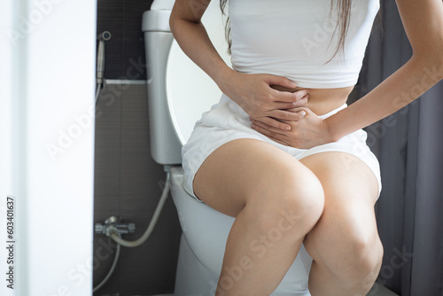 Woman sitting on the toilet having pain in her stomach. Constipation.