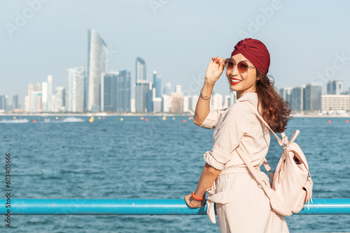 Indian Girl walking along the Corniche promenade in Abu Dhabi  UAE  with its lush greenery and clean beaches  is a great way to unwind and soak up the sun while enjoying the fresh sea breeze.