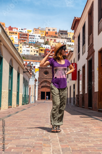 Vacation concept, woman walking through the city of San Sebastian de la Gomera next to the Iglesia De La Asuncion, Canary Islands
