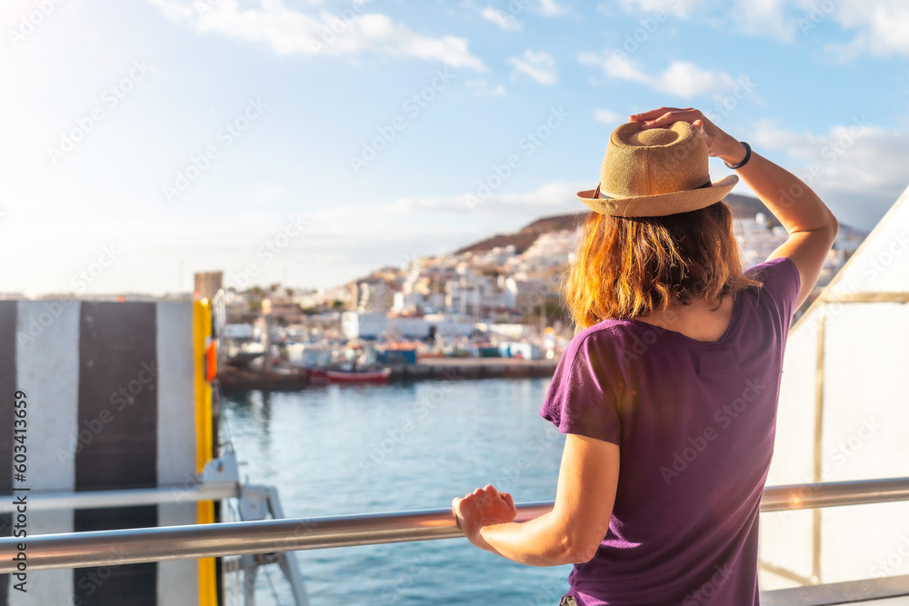 Fototapeta premium A female tourist from the Ferry and the city of Los Cristianos in the background on the island of Tenerife. Ferry coming from La Gomera, Canary Islands