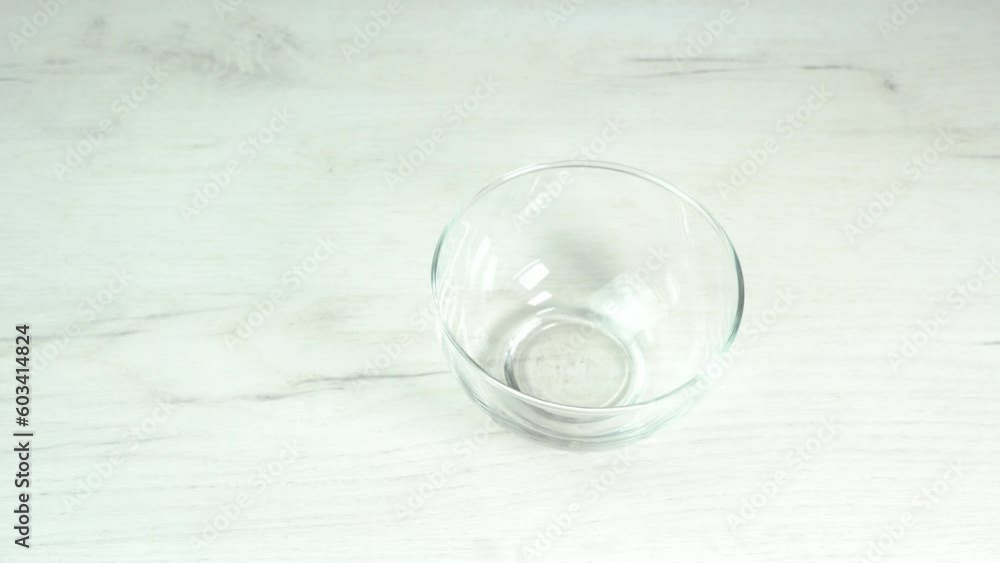 The hand puts a transparent glass bowl on the table. Equipment for cooking. Kitchen utensils for baking, pastry and dessert The hand puts a transparent glass bowl on the table. Equipment for cooking. Kitchen utensils for baking, pastry and dessert