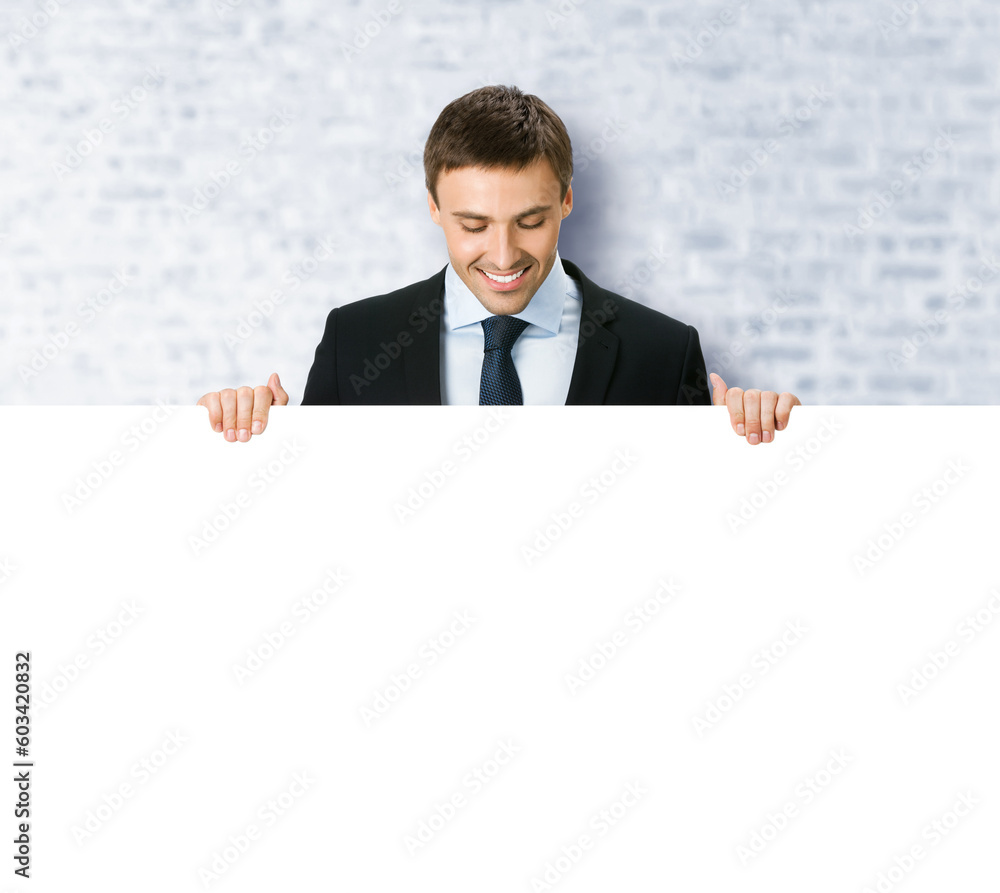 Business man professional bank manager in confident black suit. Businessman stand behind hang over, look at empty white banner signboard with copy space. White bricks office background Business man professional bank manager in confident black suit. Businessman stand behind hang over, look at empty white banner signboard with copy space. White bricks office background