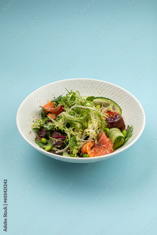 Portion of fresh gourmet salad with salmon on blue background Portion of fresh gourmet salad with salmon on blue background