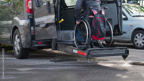 Woman on wheelchair using accessible car lift for people with disability.