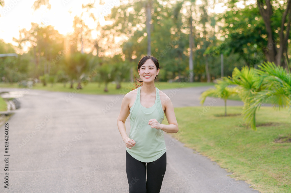 Fit Asian young woman jogging in park smiling happy running and enjoying a healthy outdoor lifestyle. Female jogger. Fitness runner girl in public park. healthy lifestyle and wellness being concept Fit Asian young woman jogging in park smiling happy running and enjoying a healthy outdoor lifestyle. Female jogger. Fitness runner girl in public park. healthy lifestyle and wellness being concept