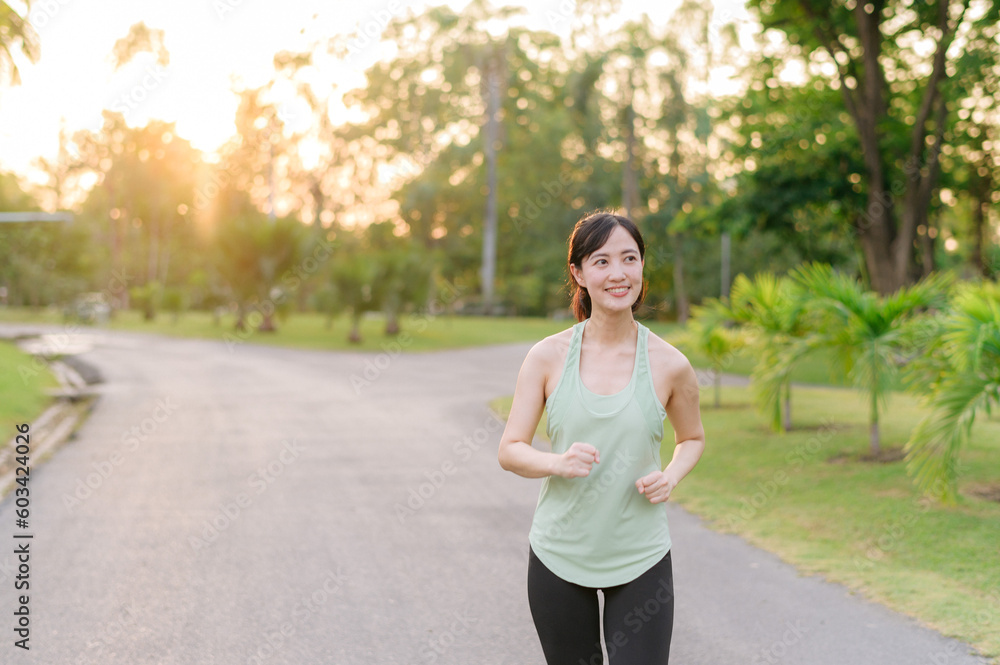 Fit Asian young woman jogging in park smiling happy running and enjoying a healthy outdoor lifestyle. Female jogger. Fitness runner girl in public park. healthy lifestyle and wellness being concept