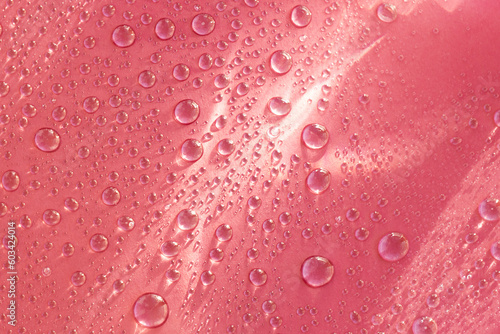 Abstract cosmetic background of a drop of moisturizing liquid on a pink background. Moisturizer tonic, lotion, serum.