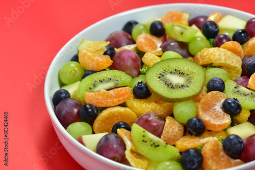 Healthy fresh fruit salad bowl on red background. Top view. Healthy food concept  healthy high vitamin fruit  mixed fruit background.