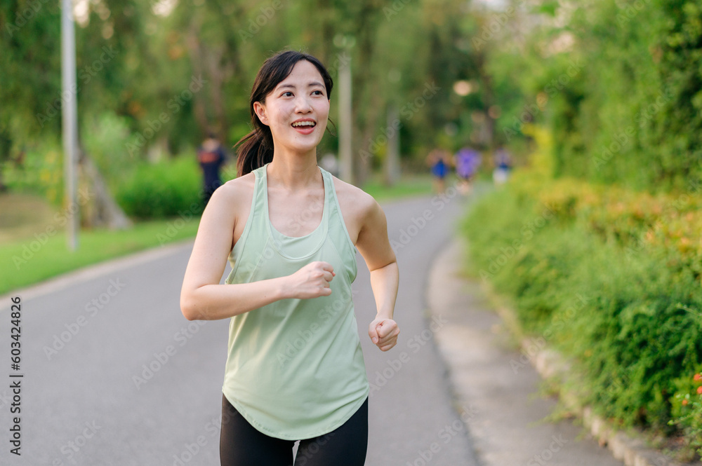 Fit Asian young woman jogging in park smiling happy running and enjoying a healthy outdoor lifestyle. Female jogger. Fitness runner girl in public park. healthy lifestyle and wellness being concept Fit Asian young woman jogging in park smiling happy running and enjoying a healthy outdoor lifestyle. Female jogger. Fitness runner girl in public park. healthy lifestyle and wellness being concept