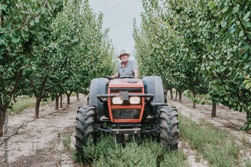 Elderly man driving tractor on farm photo