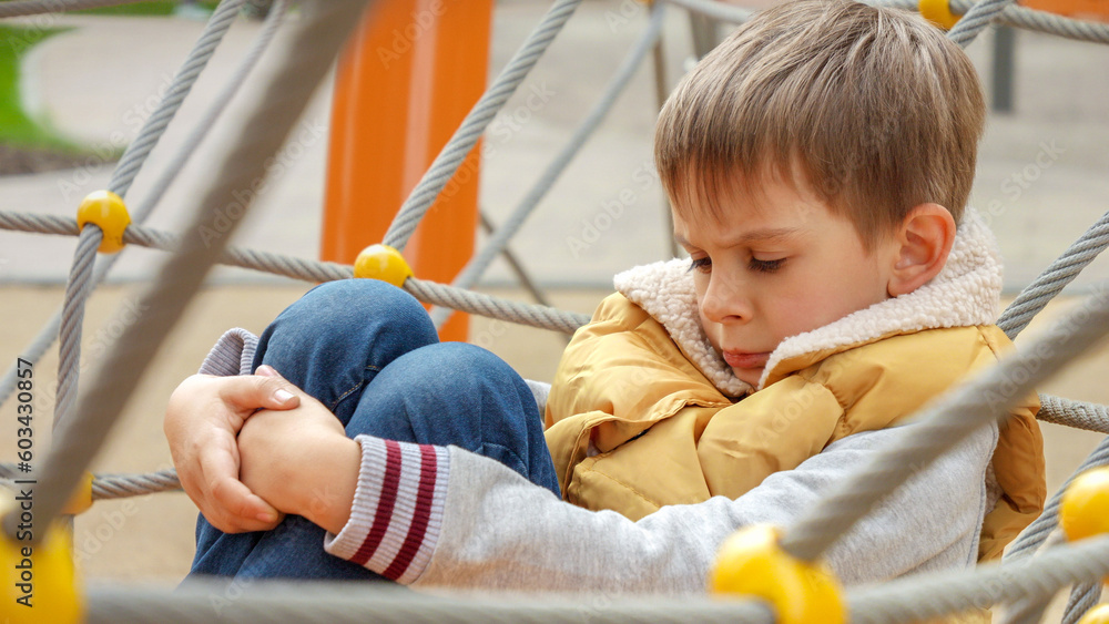 Portrait of upset little boy sitting alone on the playground and feeling sad Portrait of upset little boy sitting alone on the playground and feeling sad