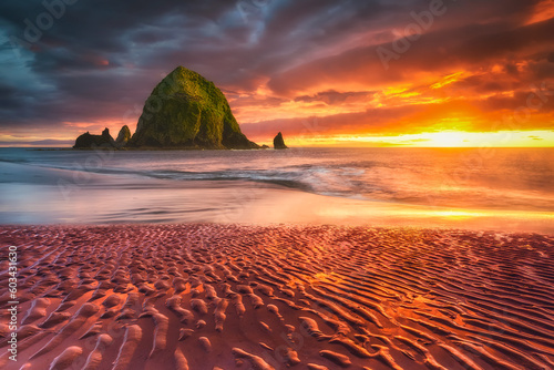 Beautiful view at sunset of Cannon Beach with Haystack Rock in the background and sand textures on the foreground. Colorful summer sunset over Haystack Rock in Cannon Beach (Oregon coast), USA	
