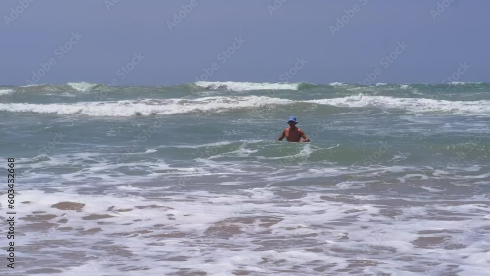 happy mature man, healthy senior 60 years old in ocean waves, swims in open sea, improve health, concept dangers of rips, learning swimming skills, vacation and travel, climate change, global warming happy mature man, healthy senior 60 years old in ocean waves, swims in open sea, improve health, concept dangers of rips, learning swimming skills, vacation and travel, climate change, global warming
