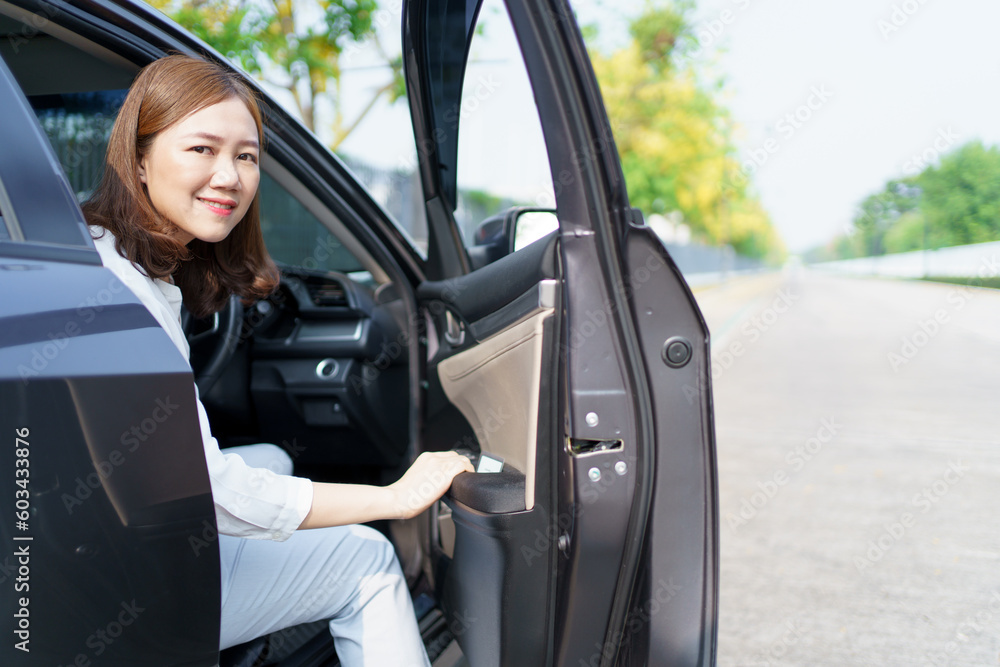 Happy cheerful Asian woman getting in or getting out of the car from driver position, female driver smiles and looks at camera. Happy cheerful Asian woman getting in or getting out of the car from driver position, female driver smiles and looks at camera.